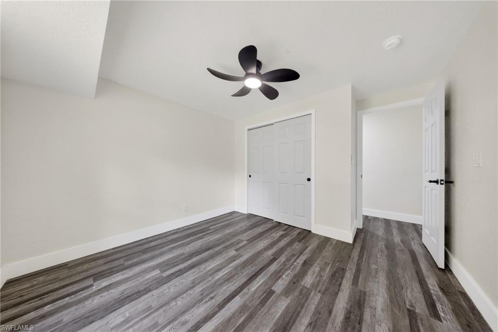 Room featuring wood-finish flooring, a contemporary ceiling fan, white bi-fold closet doors, and crisp white trim