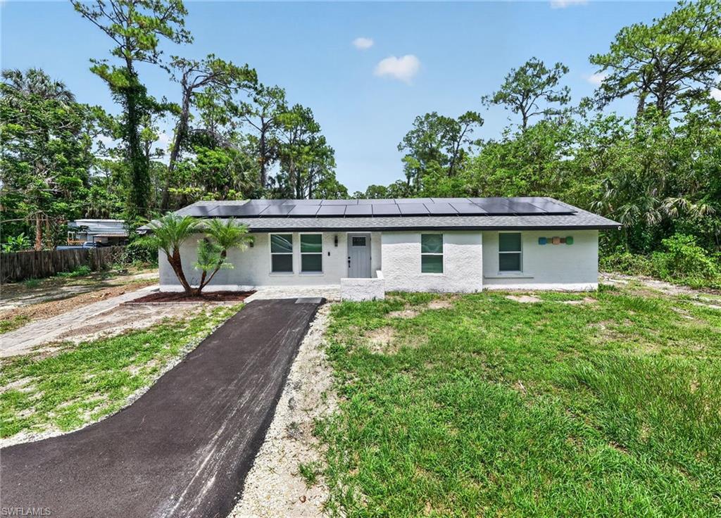 White stucco exterior with a dark shingle roof featuring solar panels
