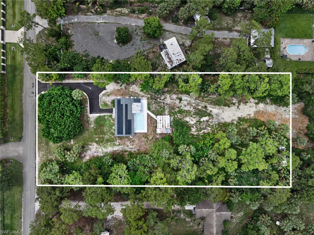Modern residence featuring a rectangular swimming pool, solar panels, and a paved driveway