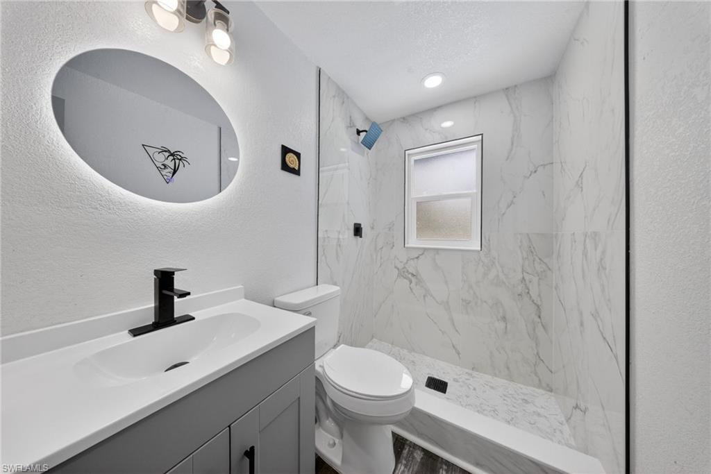 Bathroom featuring a contemporary vanity with an integrated sink, matte black faucet, and backlit oval mirror