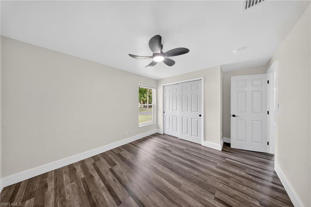 Interior room featuring wood-finish flooring, light neutral-toned walls, and a contemporary ceiling fan