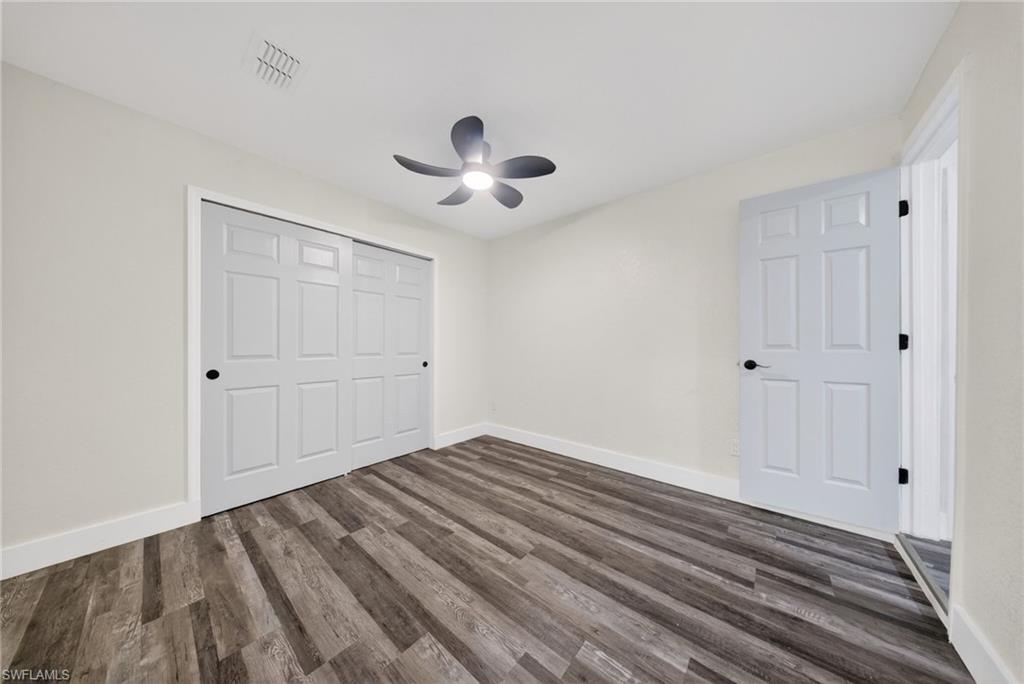 Spacious room featuring wood-finish flooring, a contemporary ceiling fan, and large sliding closet doors