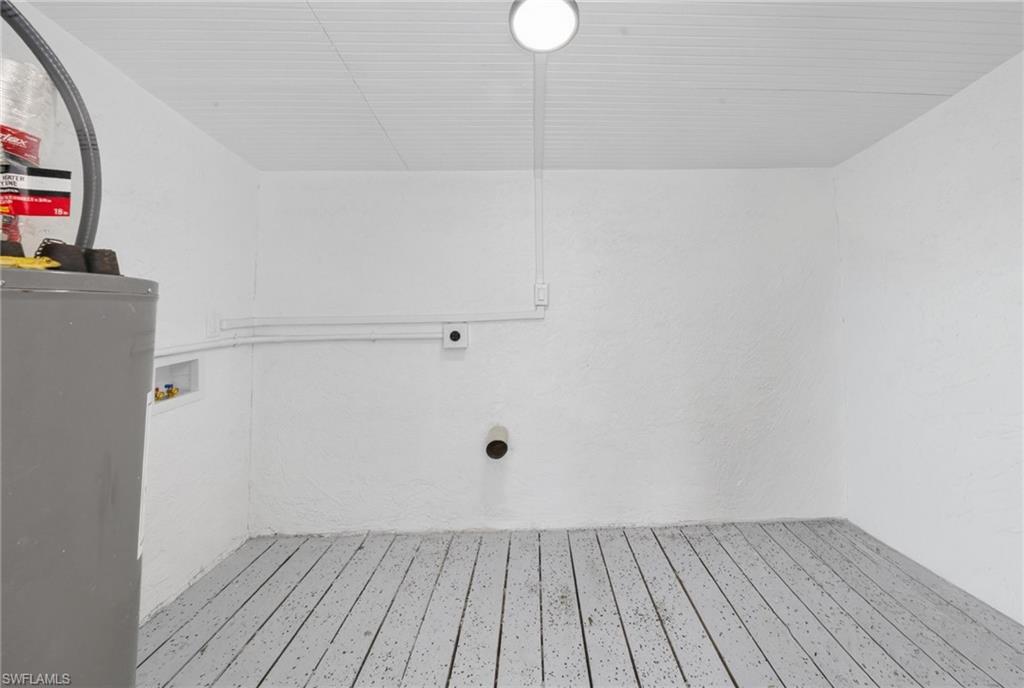 Dedicated utility area with painted wood-finish flooring, a smooth white ceiling, and a flush-mount circular light fixture