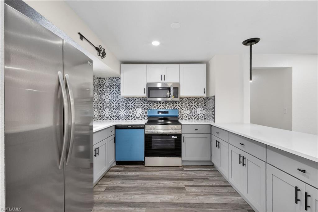 Modern kitchen featuring wood-finish flooring, white countertops, and a striking patterned tile backsplash