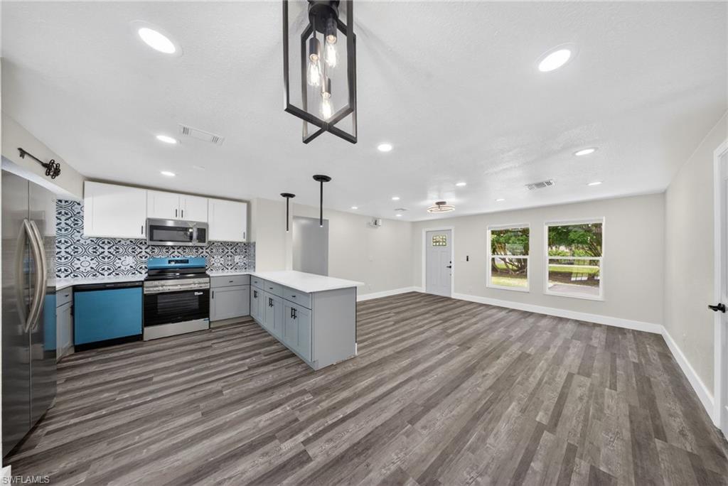 Open-concept living area featuring wood-finish flooring, recessed lighting, and a modern kitchen