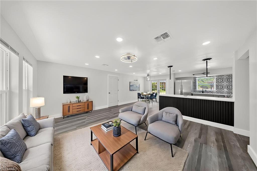 Open-concept living space featuring wood-finish flooring, recessed lighting, and ample natural light from multiple windows