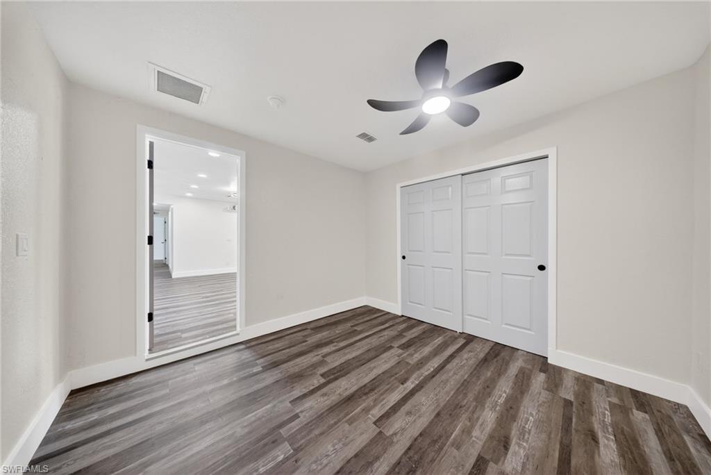 Spacious room featuring wood-finish flooring, light-toned walls, and white baseboards