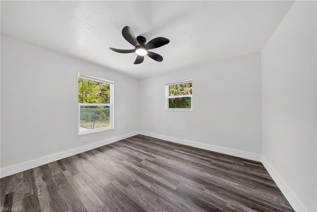 Spacious room featuring wood-finish flooring, white baseboards, and light gray walls