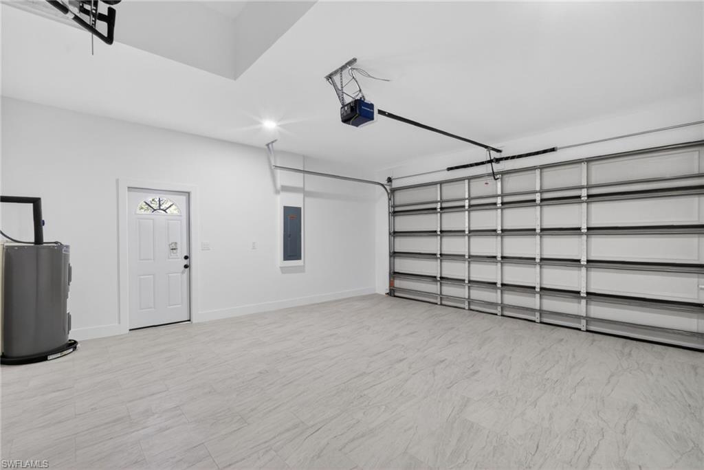 Spacious garage featuring light-toned tile flooring and a sectional overhead door with an automatic opener