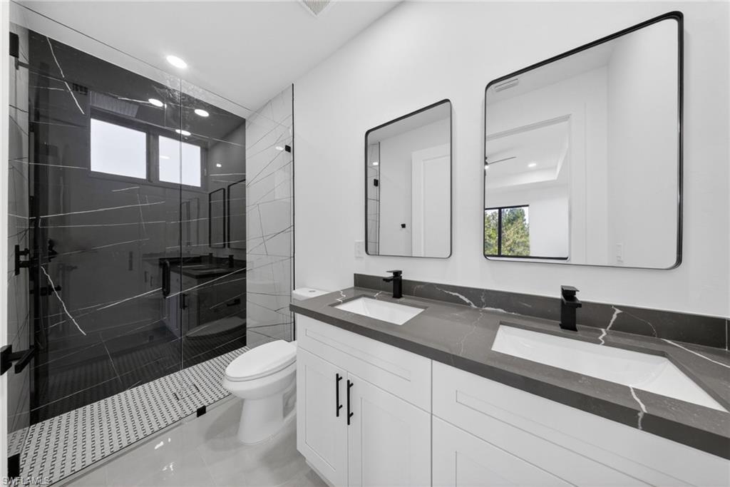 Contemporary bathroom featuring a spacious glass-enclosed shower with black-veined wall tiles and a mosaic tile floor