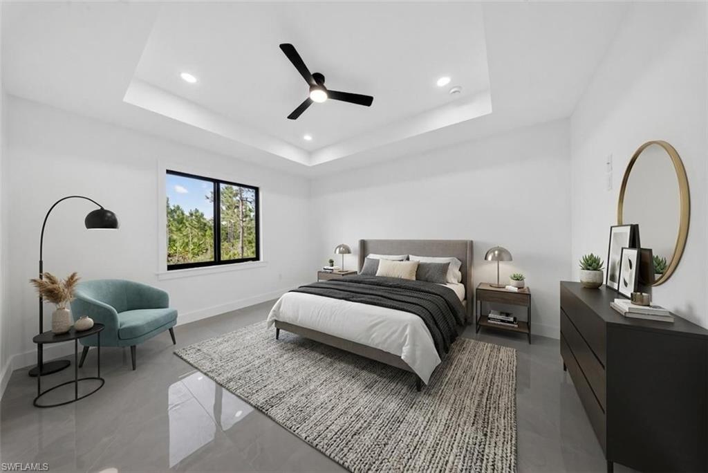 Spacious room featuring a tray ceiling with recessed lighting and a ceiling fan
