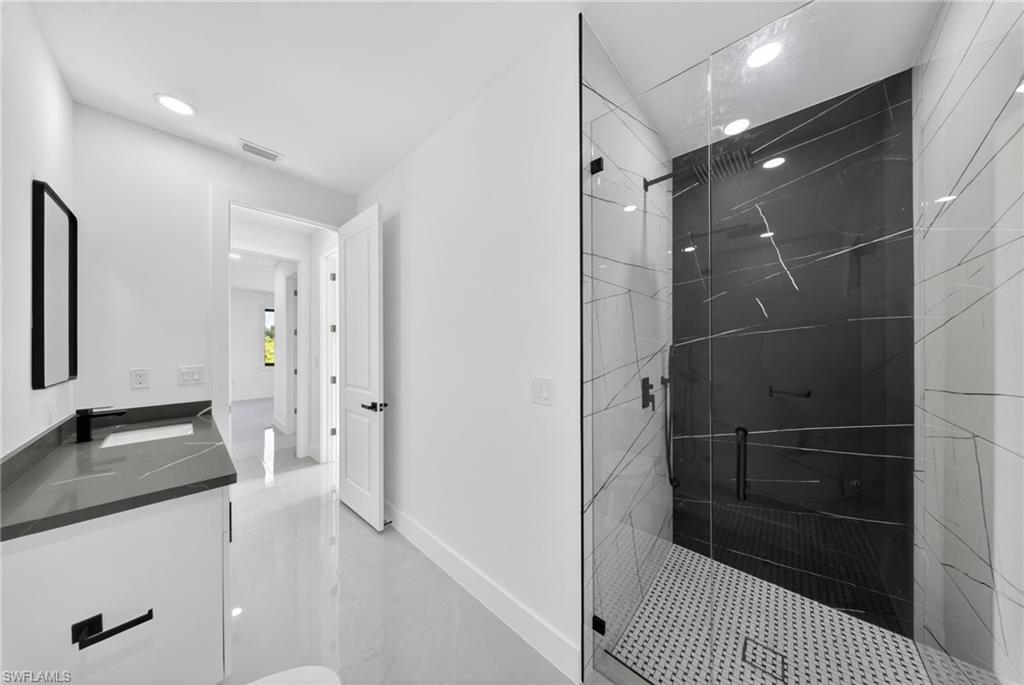 Sleek bathroom featuring a spacious glass-enclosed shower with black and white patterned tile walls
