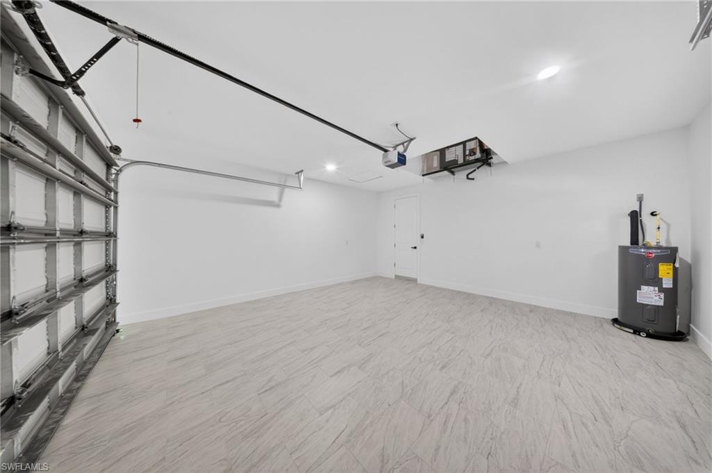 Spacious garage featuring light-toned, wood-finish flooring and a white overhead garage door