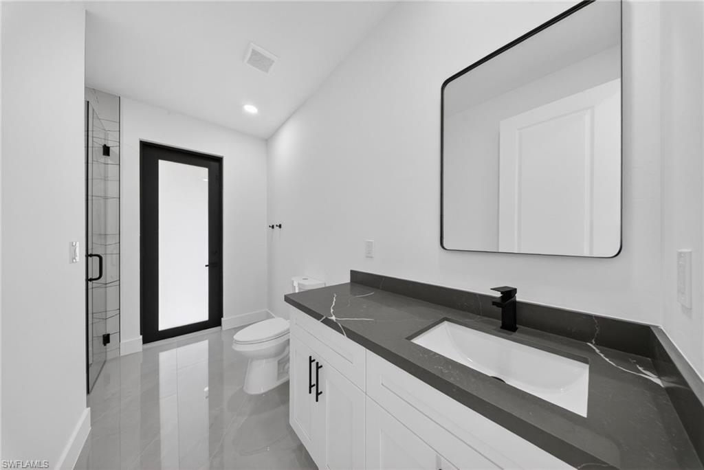 Contemporary bathroom featuring a dark grey countertop with white veining, integrated rectangular sink, and matte black faucet