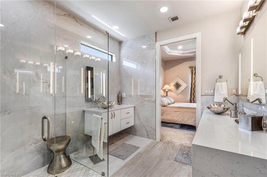 Ensuite bathroom with ensuite bathroom, recessed lighting, tile walls, visible vents, and a marble finish shower