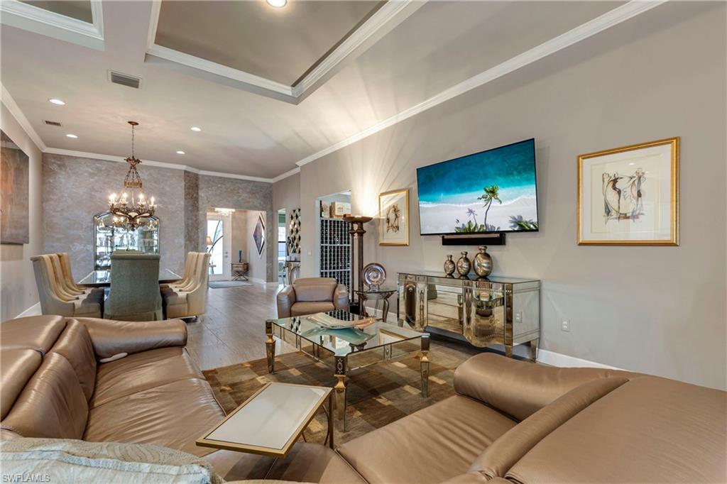 Living room with baseboards, visible vents, an inviting chandelier, crown molding, and recessed lighting