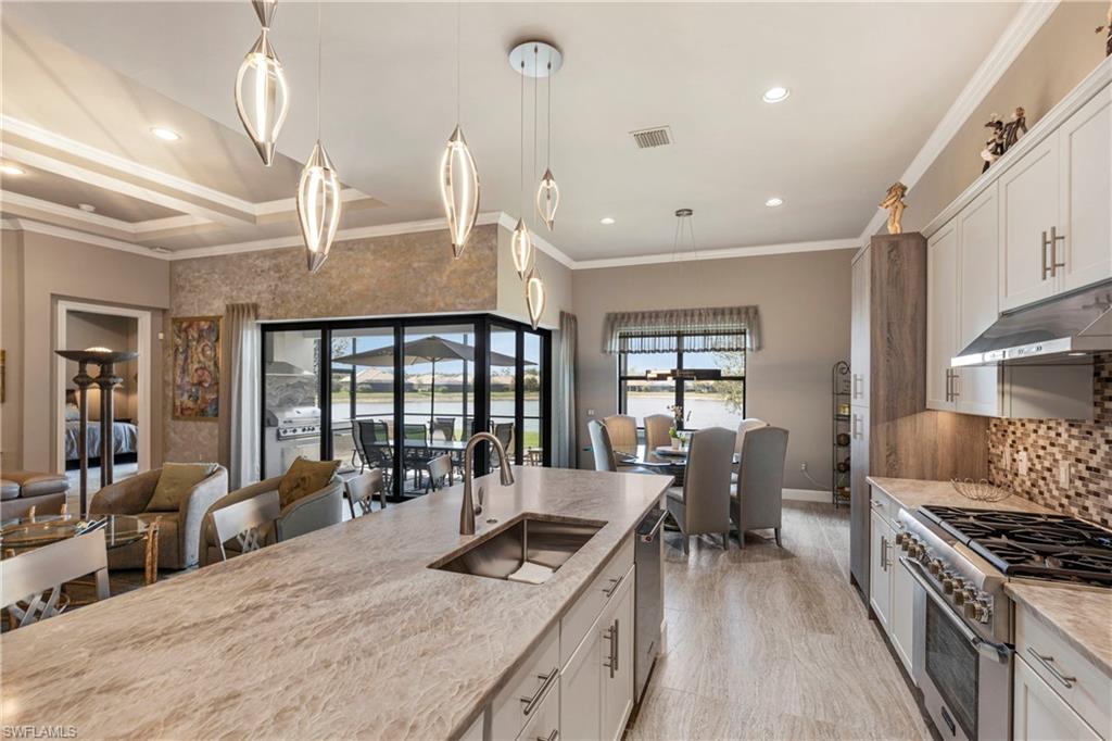 Kitchen with appliances with stainless steel finishes, a sink, white cabinetry, and under cabinet range hood