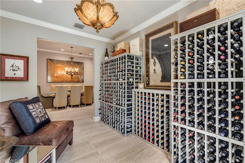 Wine cellar featuring tile patterned flooring, visible vents, a chandelier, and crown molding