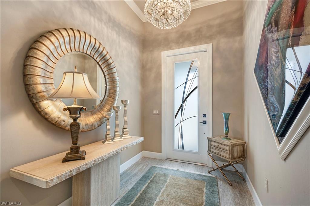 Doorway to outside with a chandelier, light wood-style floors, and baseboards