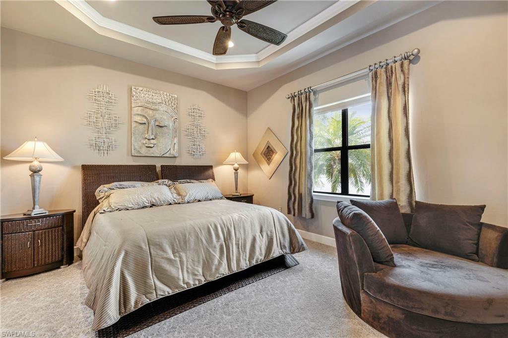 Carpeted bedroom featuring baseboards, a tray ceiling, ceiling fan, and ornamental molding