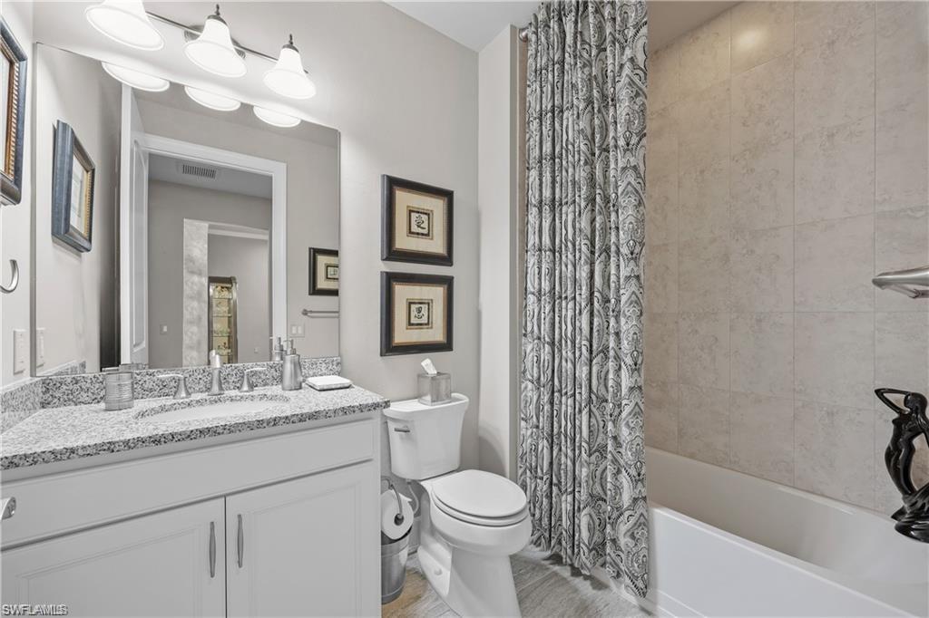 Bathroom featuring vanity and shower / bathtub combination with curtain