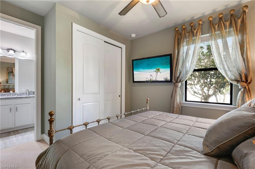 Bedroom with ceiling fan, a closet, ensuite bath, and light colored carpet