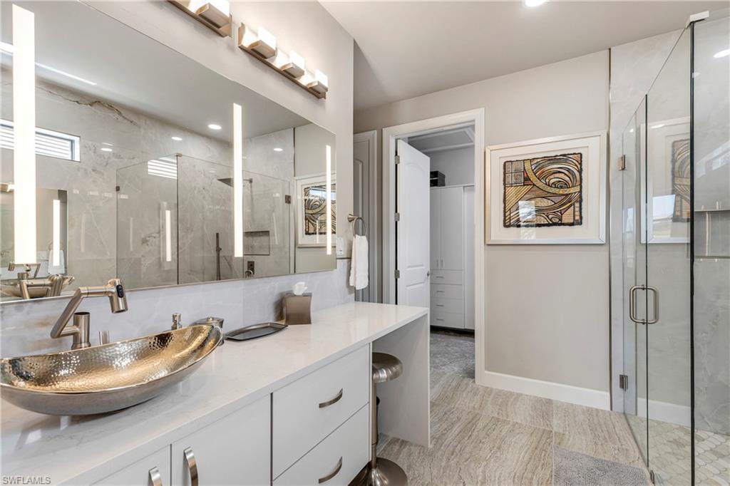 Bathroom featuring a stall shower, vanity, and baseboards