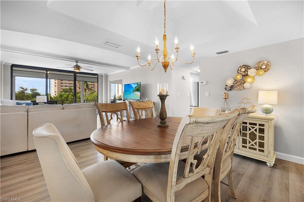 Dining area featuring wood-finish flooring, a tray ceiling, and a chandelier