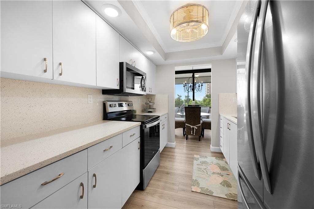 Galley kitchen featuring light wood-finish flooring, white cabinetry, and light-toned countertops
