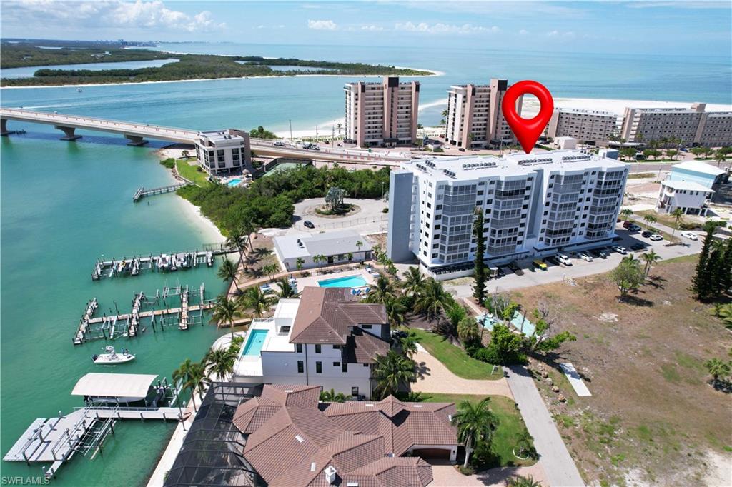 Multi-story condominium building featuring numerous balconies, a bridge over water, and multiple docks with boat slips
