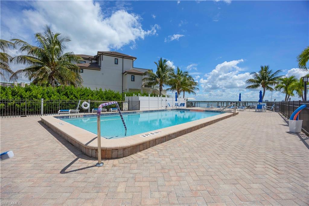 Rectangular swimming pool featuring a tiled interior, a paved surround, and a metal safety rail