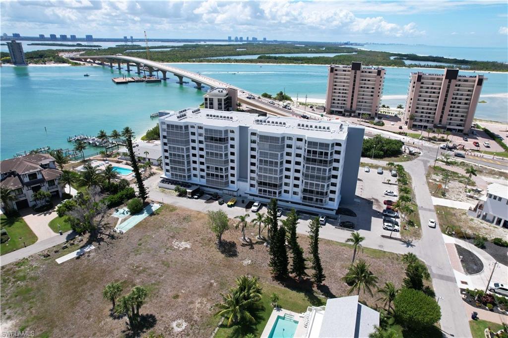 Contemporary high-rise building featuring multiple balconies overlooking a body of water with a bridge