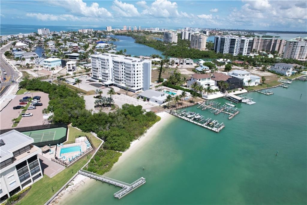 Waterfront property featuring a private marina with multiple boat slips, sandy shoreline, and a tennis court
