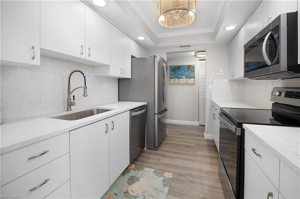 Galley kitchen featuring white cabinetry, light-toned countertops, and a white tile backsplash