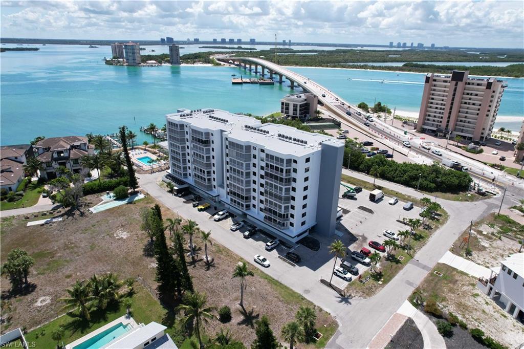 Multi-story waterfront condominium building featuring private balconies, ample parking, and a community pool