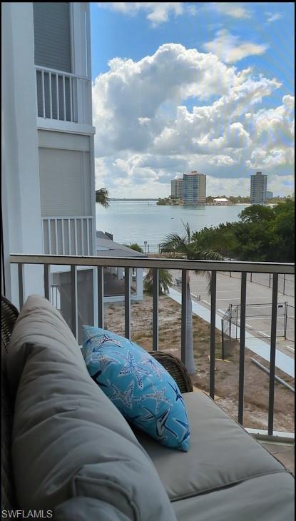 Balcony featuring water scenery with distant buildings and lush foliage