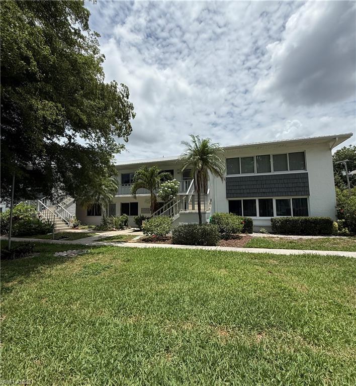 Two-story stucco structure featuring a white exterior with a gray shingle accent band