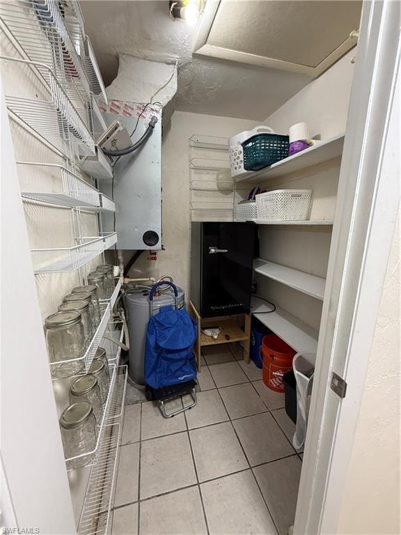 Utility closet featuring tiled flooring, a water heater, and an air handler unit