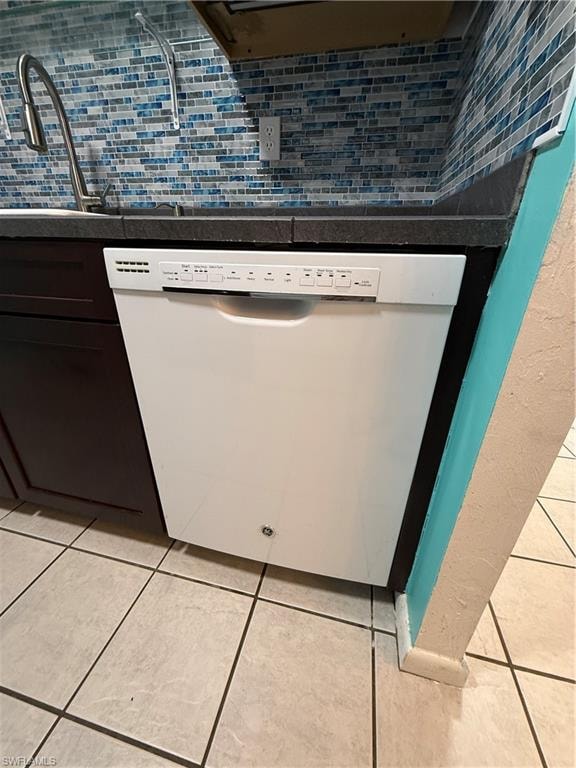 White built-in dishwasher with a dark countertop and blue mosaic tile backsplash
