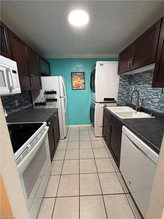 Galley kitchen featuring dark wood cabinetry, a mosaic tile backsplash, and light tile flooring