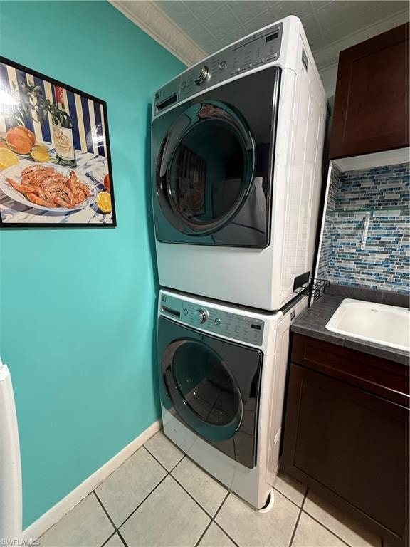 Dedicated laundry area featuring a stacked washer and dryer unit, a utility sink with a tiled backsplash, dark wood-finish cabinetry, and light-toned floor tiling