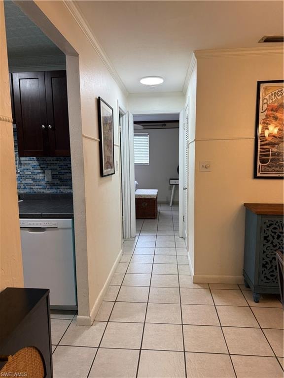 Hallway with light-toned square tile flooring, crown molding, and a flush-mount ceiling light