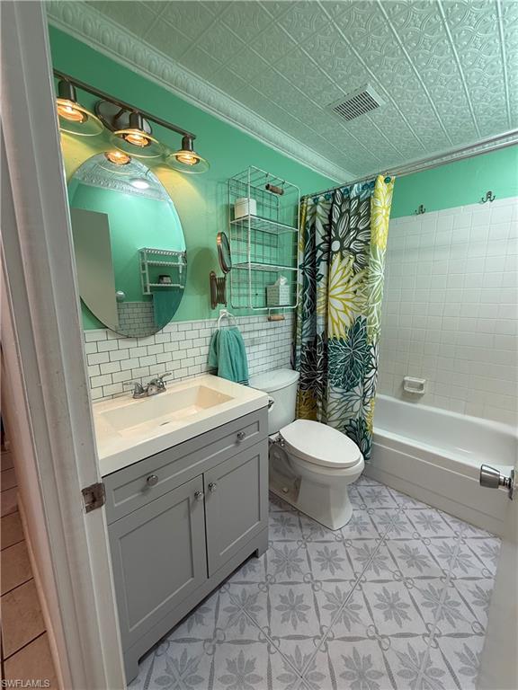 Bathroom featuring a patterned tile floor, white subway tile accent wall, and a full-size bathtub with white tile surround