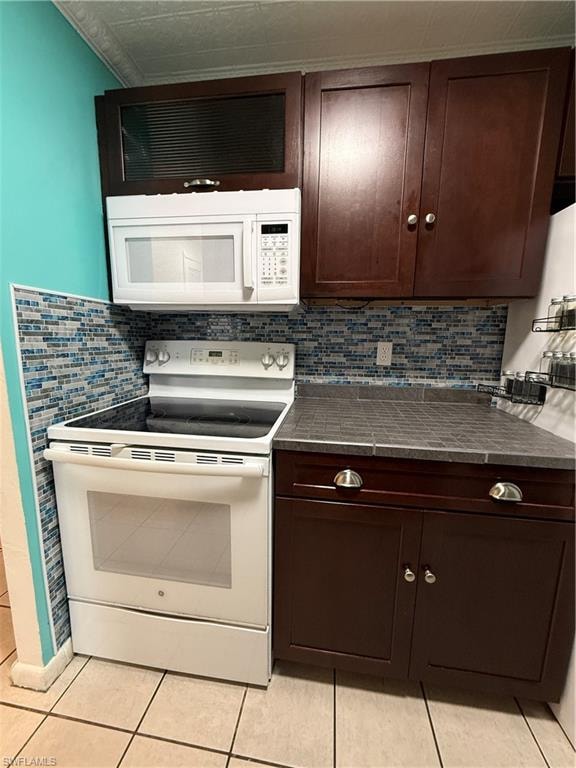 Kitchen workspace featuring a white electric range, white over-the-range microwave, dark wood-finish cabinetry, and a mosaic tile backsplash