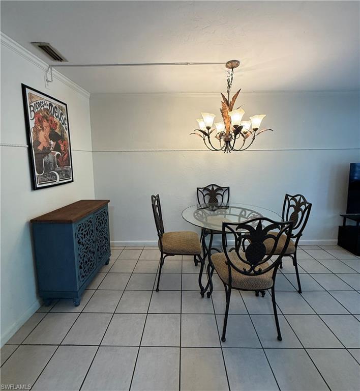 Dining area featuring a decorative chandelier, crown molding, and tiled flooring