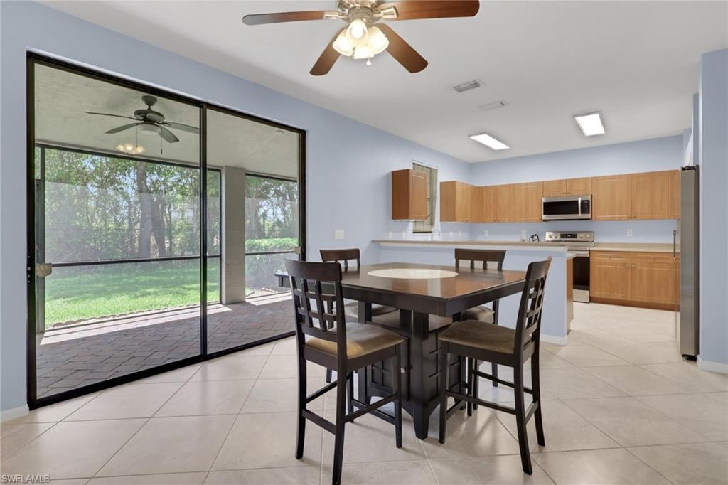 Kitchen and dining area featuring cabinetry, stainless steel appliances, and a breakfast bar.