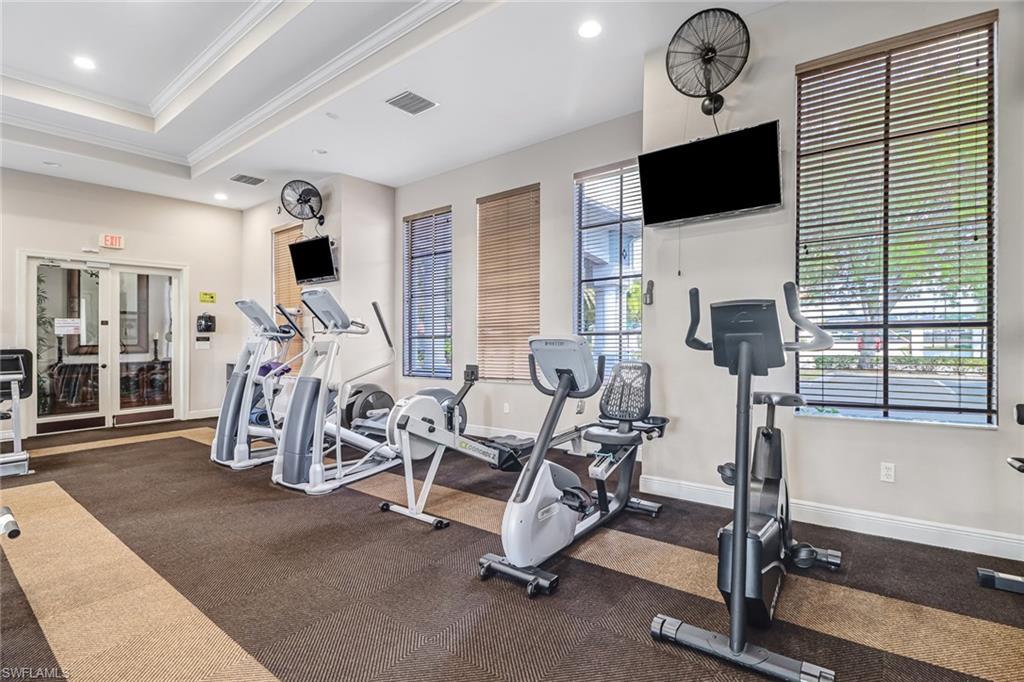 Dedicated fitness space featuring multiple exercise machines, recessed lighting, and wall-mounted televisions