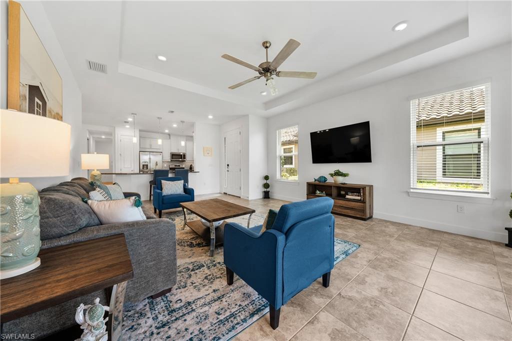 Open-concept living area featuring tray ceilings, recessed lighting, and tile flooring