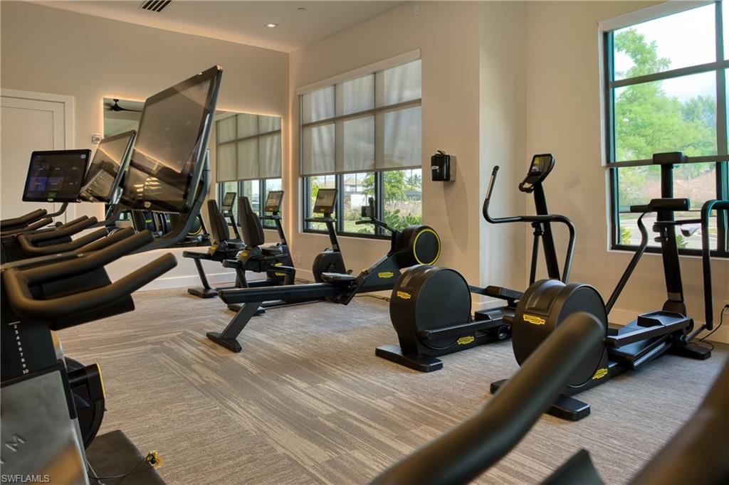 Fitness center featuring patterned carpet flooring and ample natural light through large windows