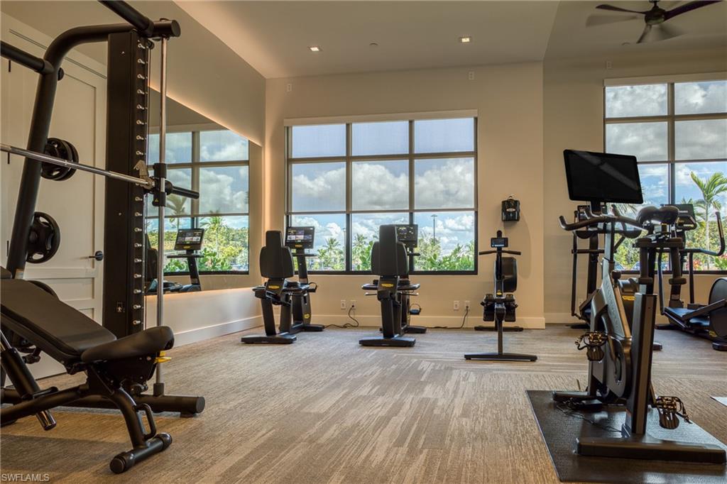 Dedicated fitness space featuring large windows, patterned carpet flooring, recessed lighting, a ceiling fan, and a full-wall mirror